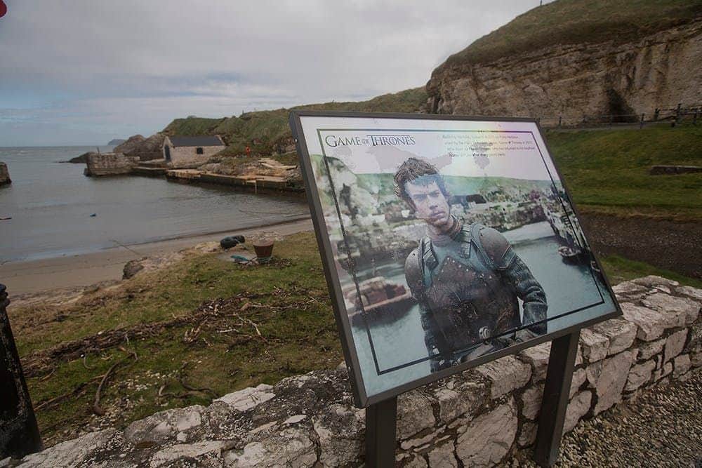 Panneau d'information représentant un personnage de "Game of Thrones" sur fond de collines et d'eau.